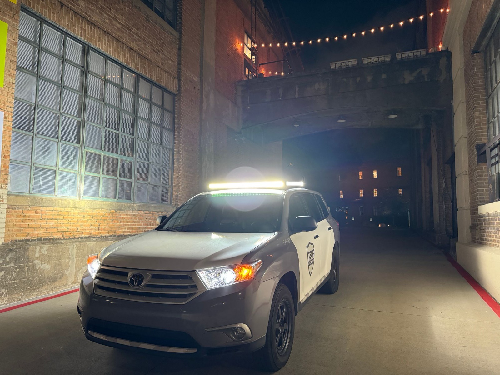 ISG patrol vehicle lighting up an alley between brick warehouses at night