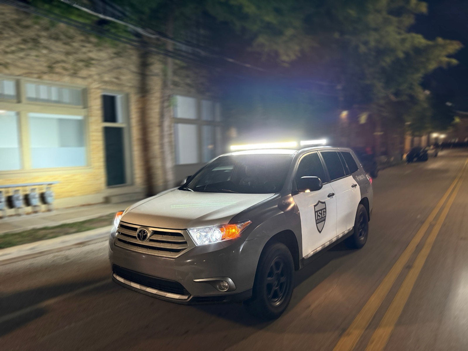 ISG patrol vehicle driving down a Dallas street at night with its light bar on